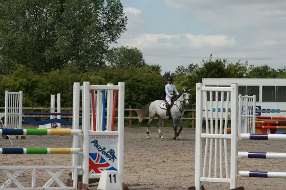 A grey cantering in the outdoor arena