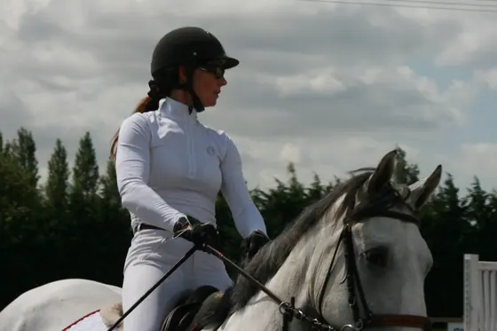 A rider on a grey looking across the arena