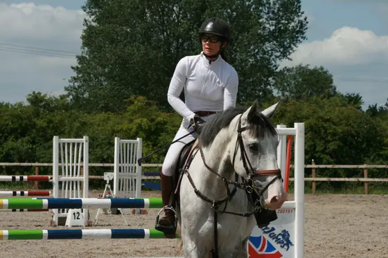 A rider on a grey at the side of the arena