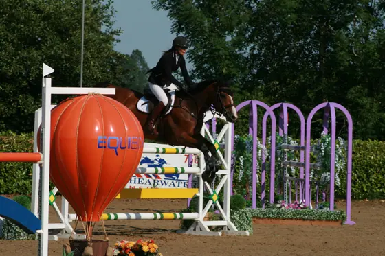 A bay jumping beside an orange balloon filler