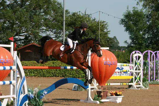 A bay jumping beside an orange balloon